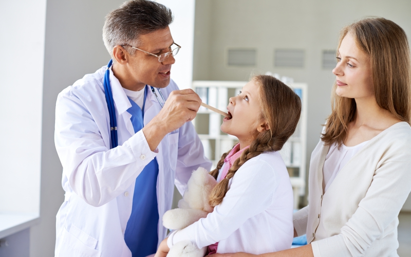 parent and adult child sitting with a doctor, discussing healthcare at childcare hospital